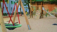 Zu sehen ist der neue Spielplatz auf dem Pfarrer-Bleek-Platz, im Vordergrund die Schaukel und im Hintergrund der Spielturm inklusive Rutsche