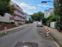 Eine Straße mit rot-weißen Pfosten, die die Fahrbahn zugunsten der Fußgänger verengen.
