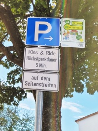 Das Verkehrsschild zeigt einen Kiss & Ride-Parkplatz sowie eine Elternhaltestelle an.