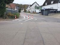 Neue Straßenmarkierungen und Pfosten als Querungshilfe auf einer breiten Kreuzung.