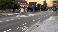 Eine neue Verkehrsinsel inmitten einer Straße inklusive Leitelementen am Gehweg.